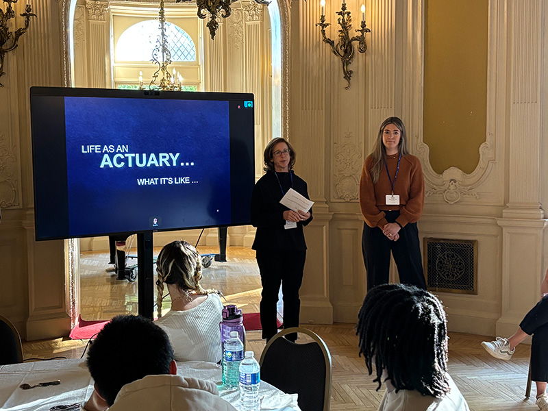 Actuaries Suzanne Martin and Natalie Pilat standing in front of the room and speaking to students about their careers.