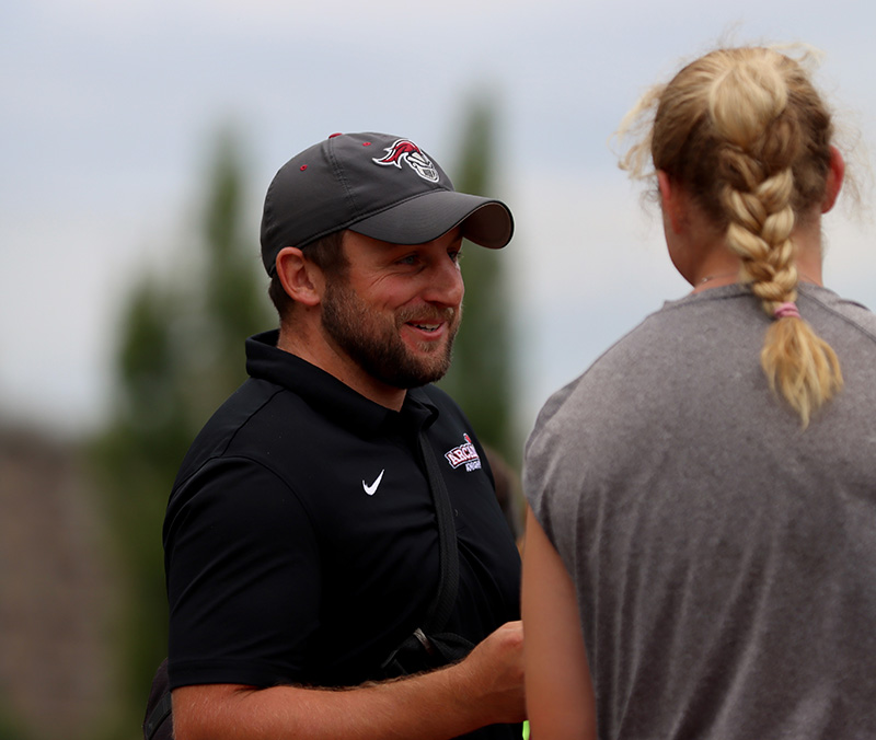 Associate Athletic Trainer Paul Diorio speaks with a student-athlete on the side of the practice field