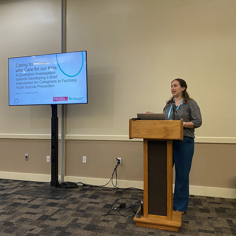 Dr. Karen Schwartz stands behind a lectern to present a talk at the DreamIPC conference.