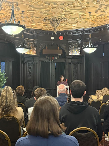 Arcadia's Tracey Levine reads from her new collection of short stories. She is in front of an audience and standing behind a lectern.