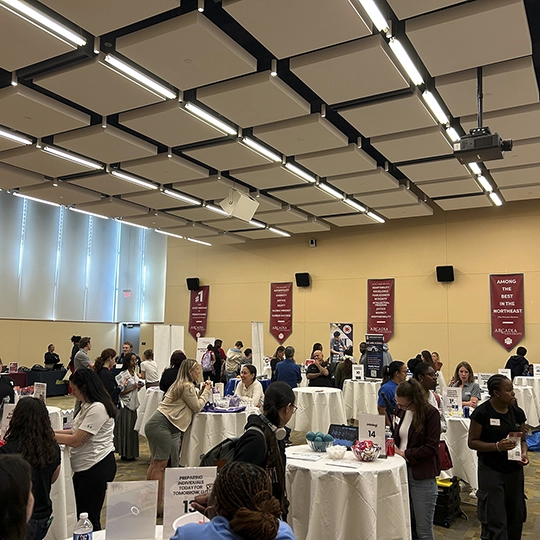Business people stand around event tables decorated with pipe and drape.