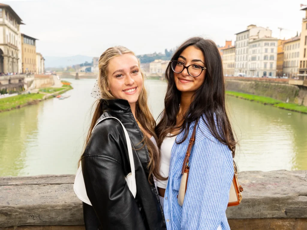 Two women pose for a photo on a bridge in Florence, Italy.