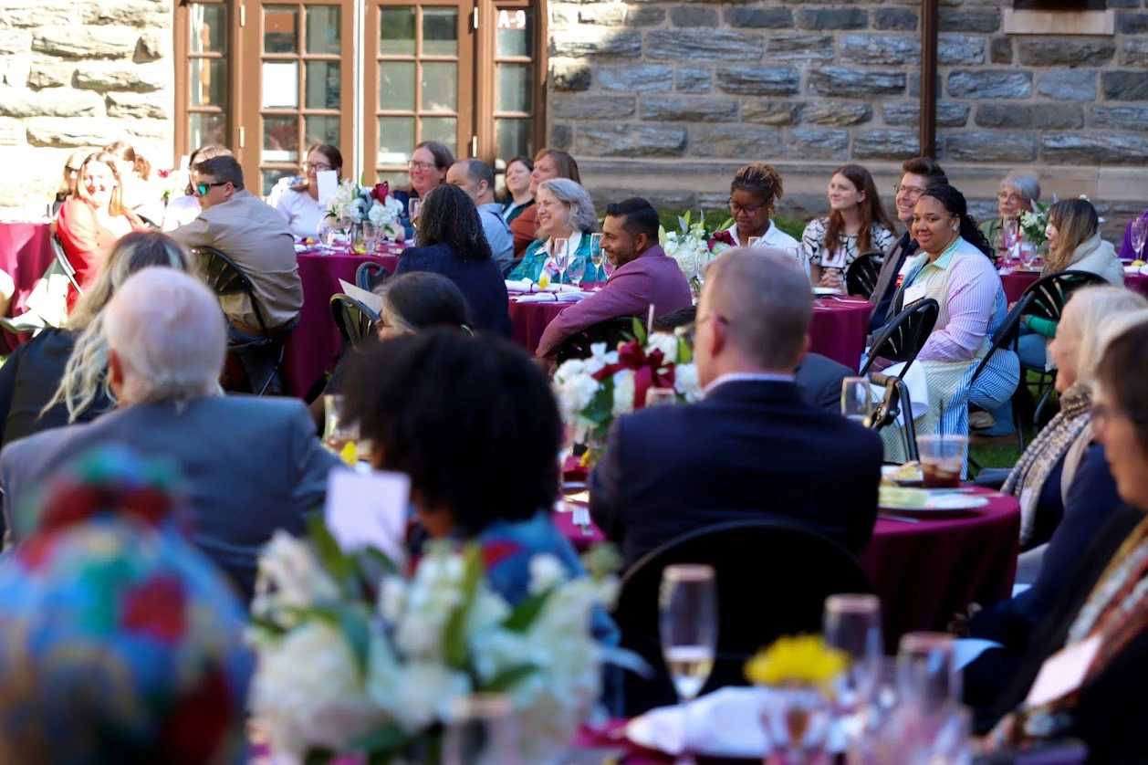 Event attendees sitting at round, full tables listening to speeches.