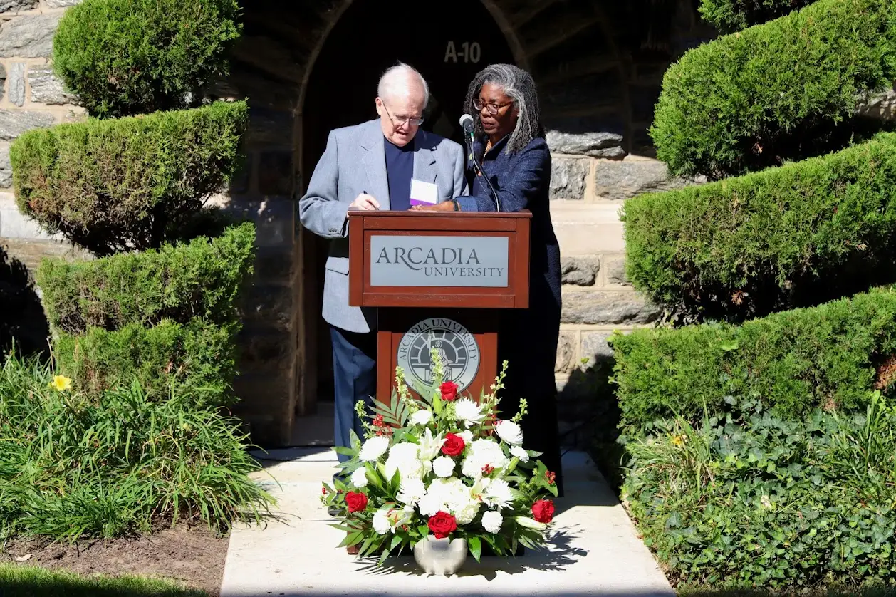 Man and woman standing at the podium getting ready to sign a document.