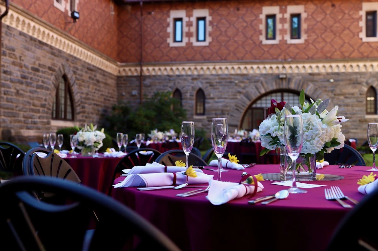 Scarlet red table cloth with beautiful setting including florals with a blue sky backdrop.