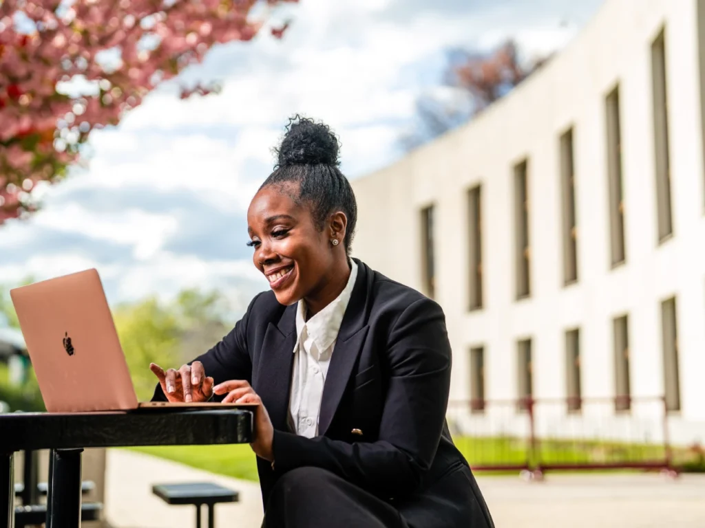 A woman sits on her laptop outside of the Landman Library.