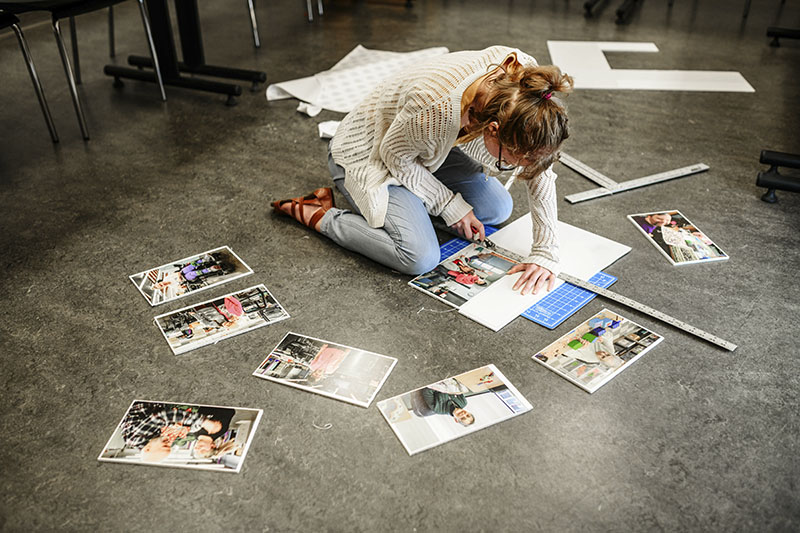 An overhead view of a student doing a big paper-based project on the floor.