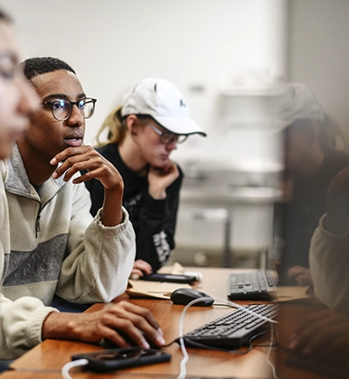 A reflection glares the screen as student work on computers in class.