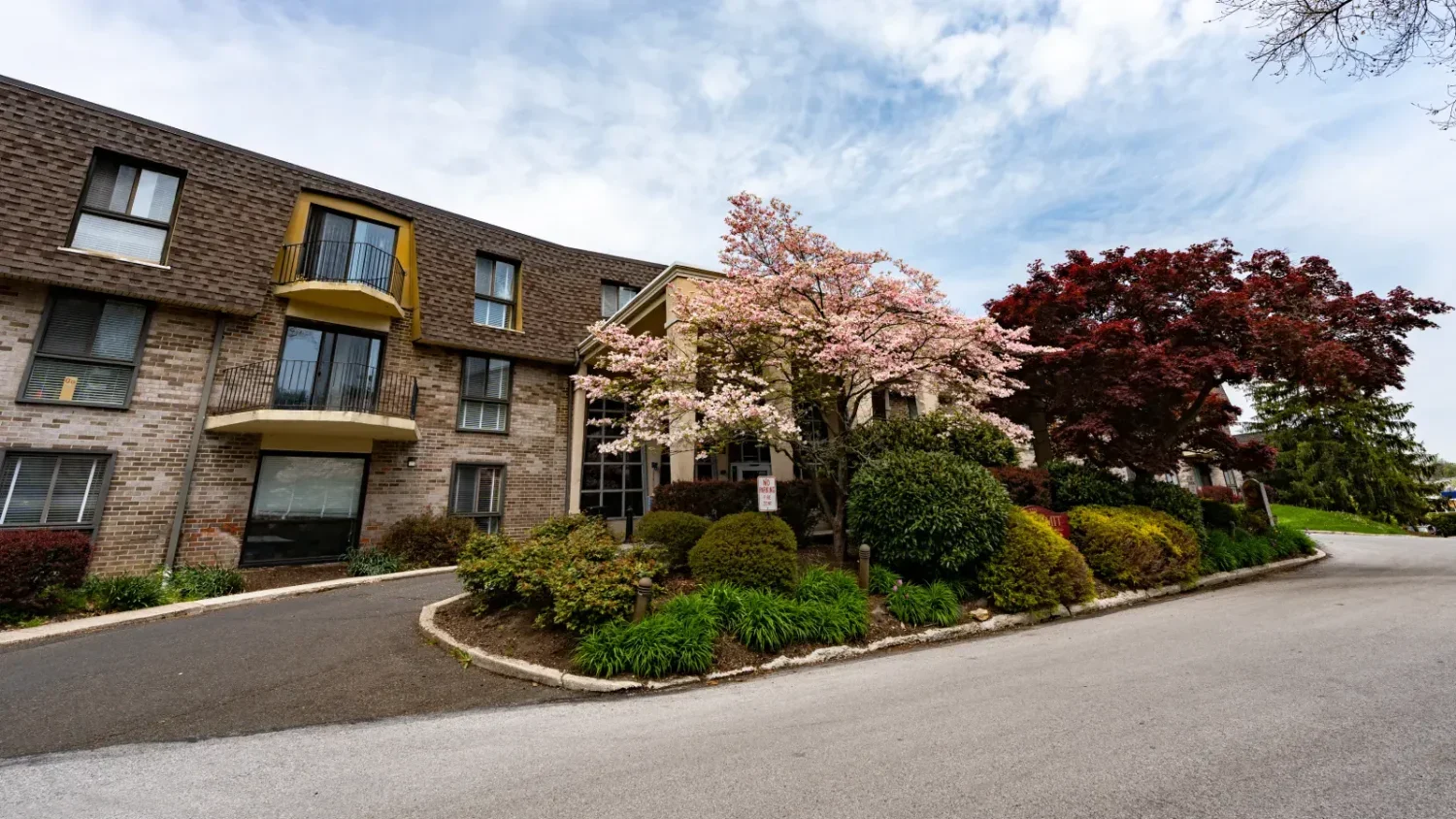 A view of the entrance of the Oak Summit Apartments with a cherry blossom tree in full bloom.