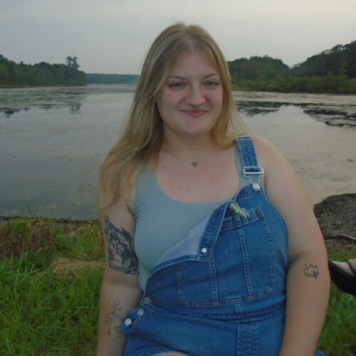 Emily Rooney ’29 standing in front of a lake.