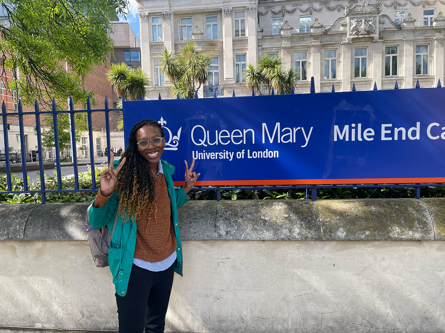 Rowana Abbensetts-Dobson ’26MFA in front of a Queen Mary University of London sign.