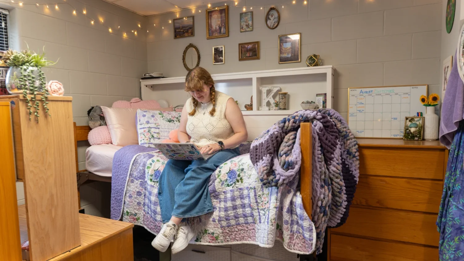 A student uses her laptop while sitting on her bed in her bedroom in the Knight Hall.