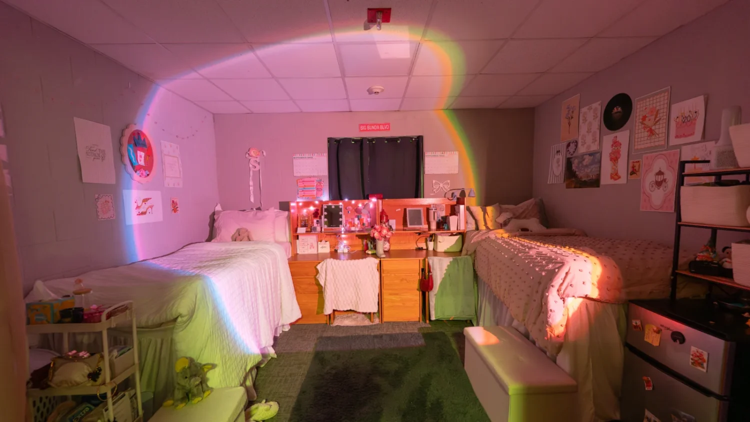 A view inside a bedroom in the Knight Hall with pink lighting and two beds positioned on opposite sides of the room.