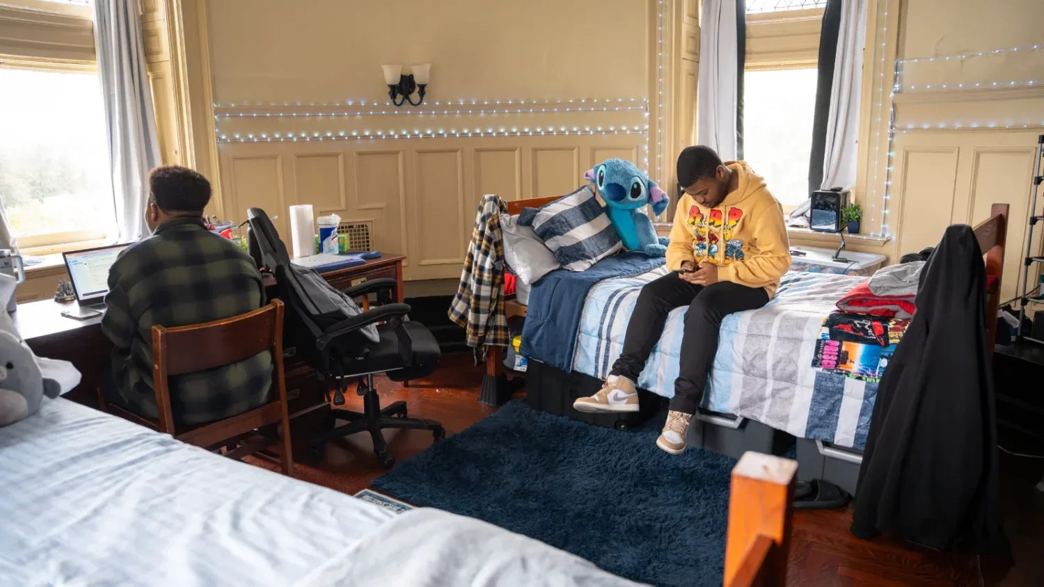 One student works on his laptop at his desk while another sits on his bed using his phone while in their shared room in Grey Towers Castle.