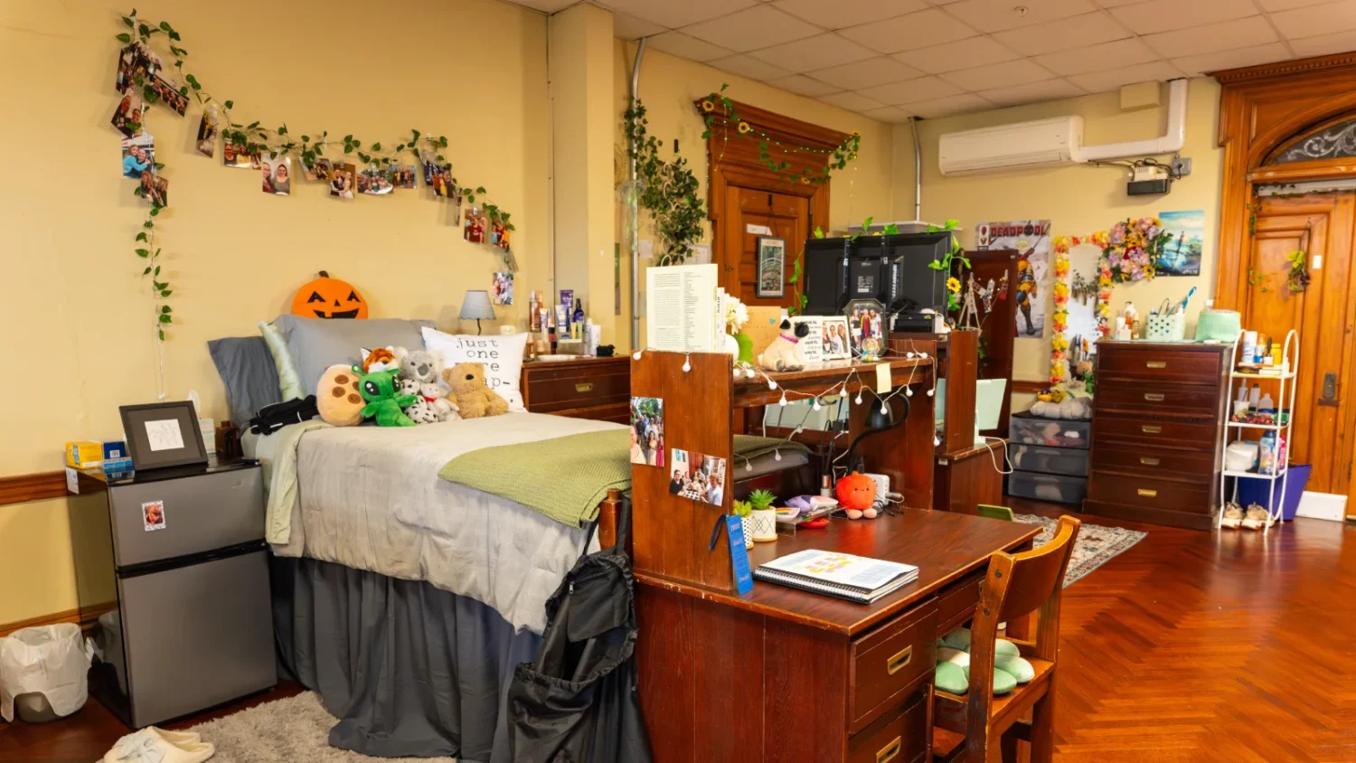 A look at one of the rooms in Grey Towers Castle where a bed is positioned with its pillows against a wall. The room is decorated with photos and greenery.
