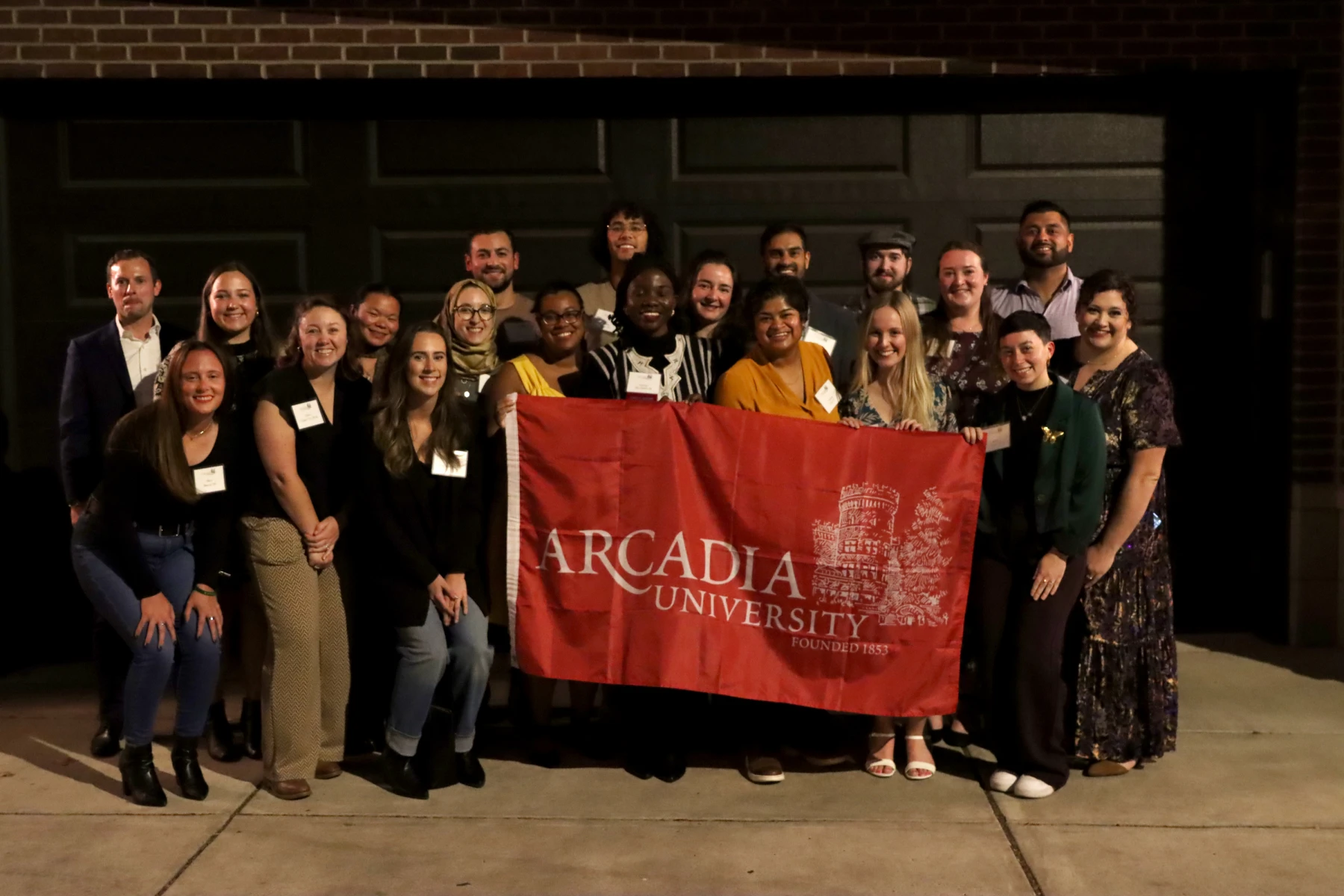 40 Under 40 honorees smile and hold up a red Arcadia University flag.