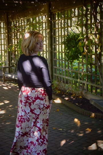 A student wearing a black top and red skirt turns her head toward the camera