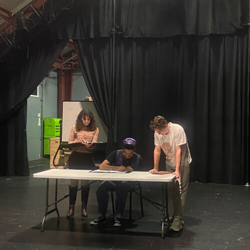 Three students working at a table in the Black Box theater.