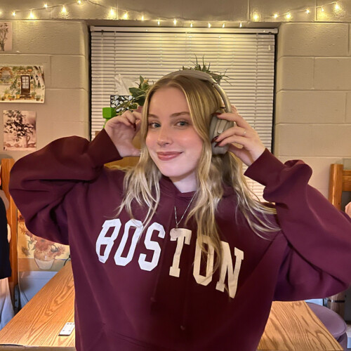 Lily Roberti ’28 putting on her headphones with a red hoodie on.