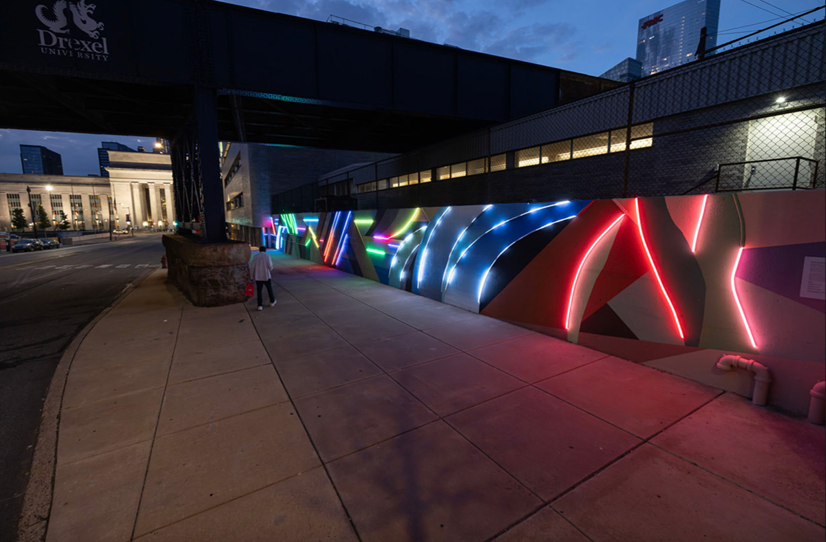 a colorful mural designed by David Guinn viewed at night