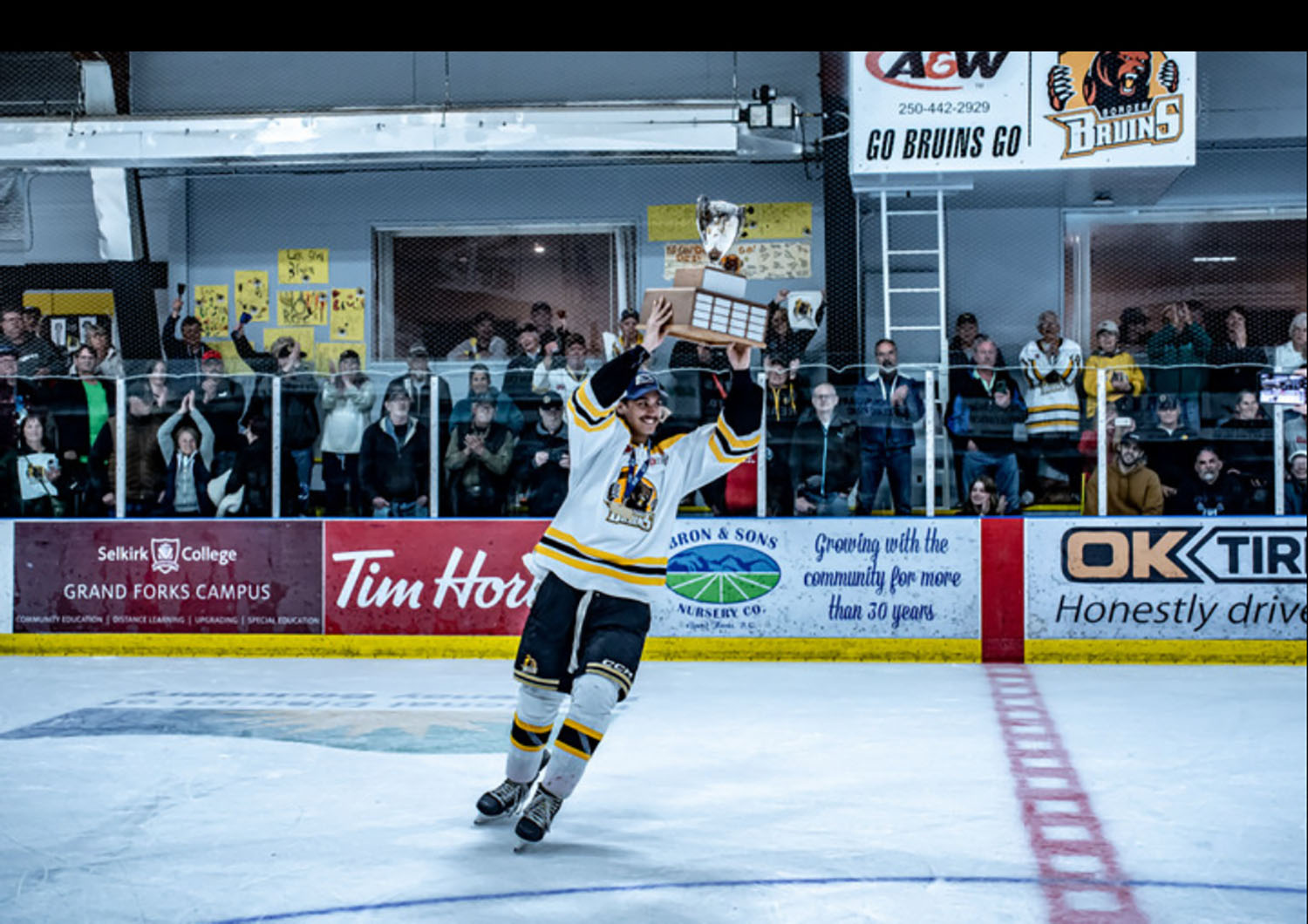 Theo Naidu ’29 holding a trophy on the ice.