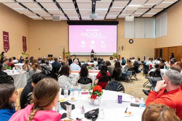 A speaker sands in front of a crowd at the Honors Breakfast event.