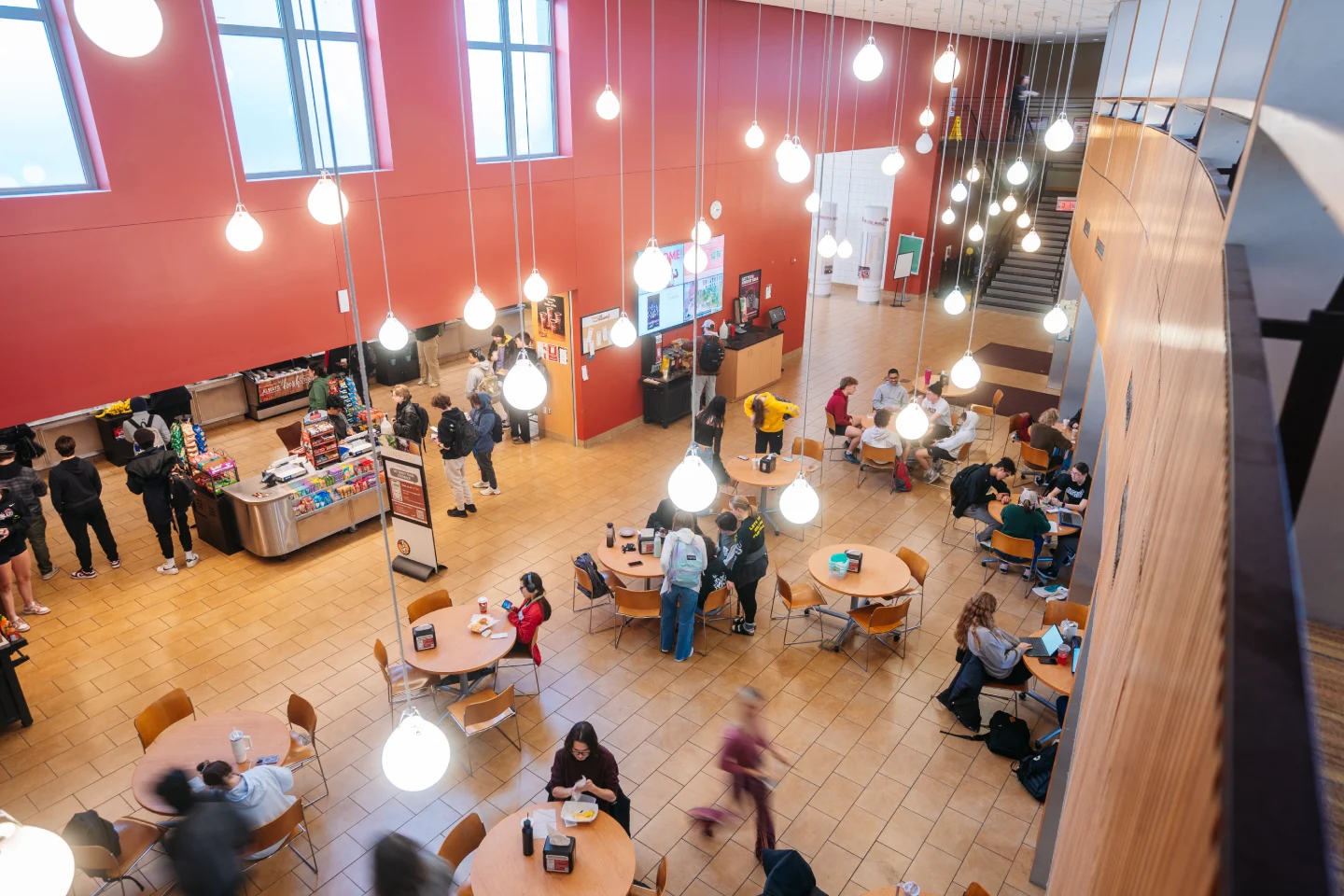 An overhead view of the Chat, located in the Commons, where students are sitting, eating, and standing in line to get food.