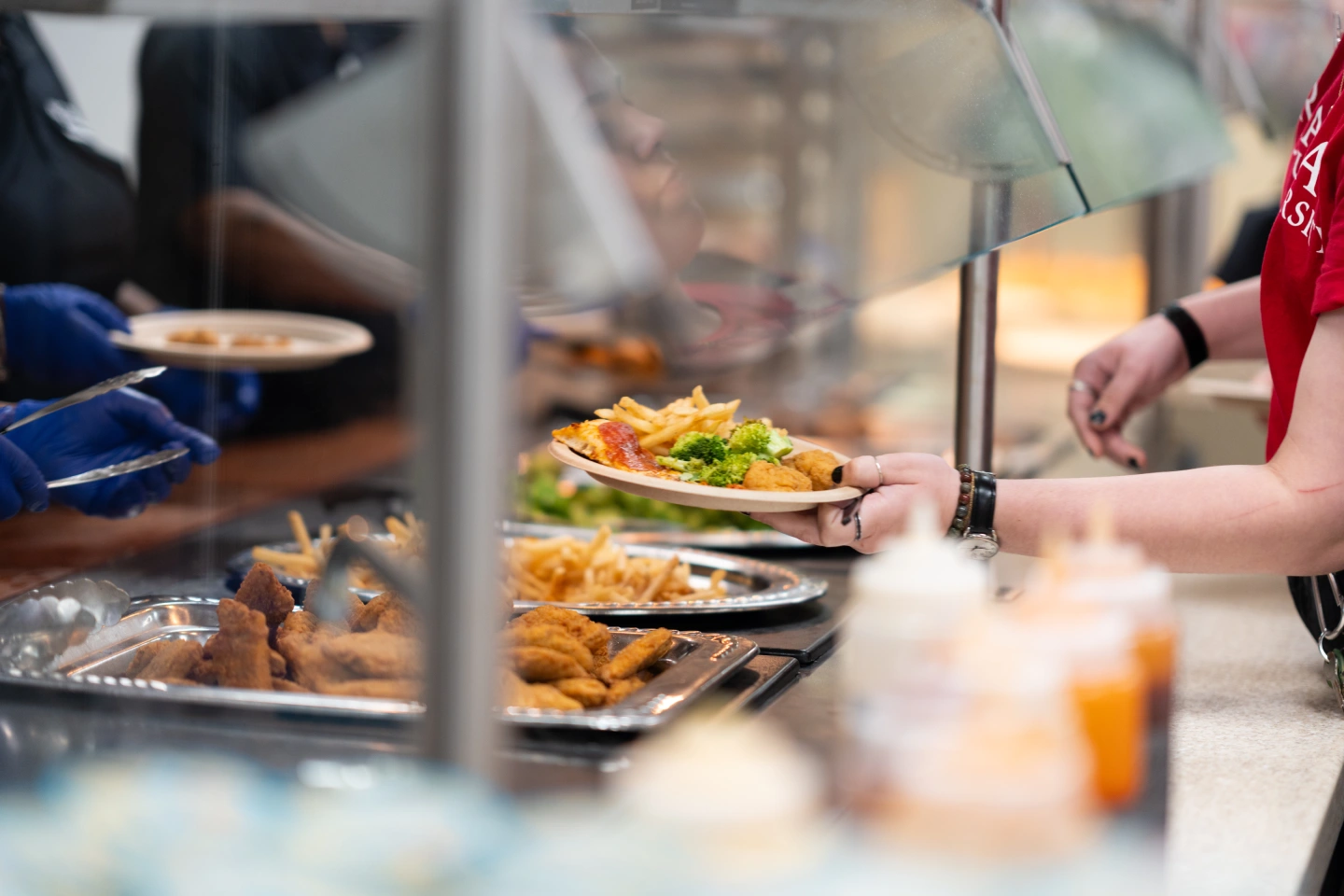A student receives food from the Cafeteria at the Dining Hall.