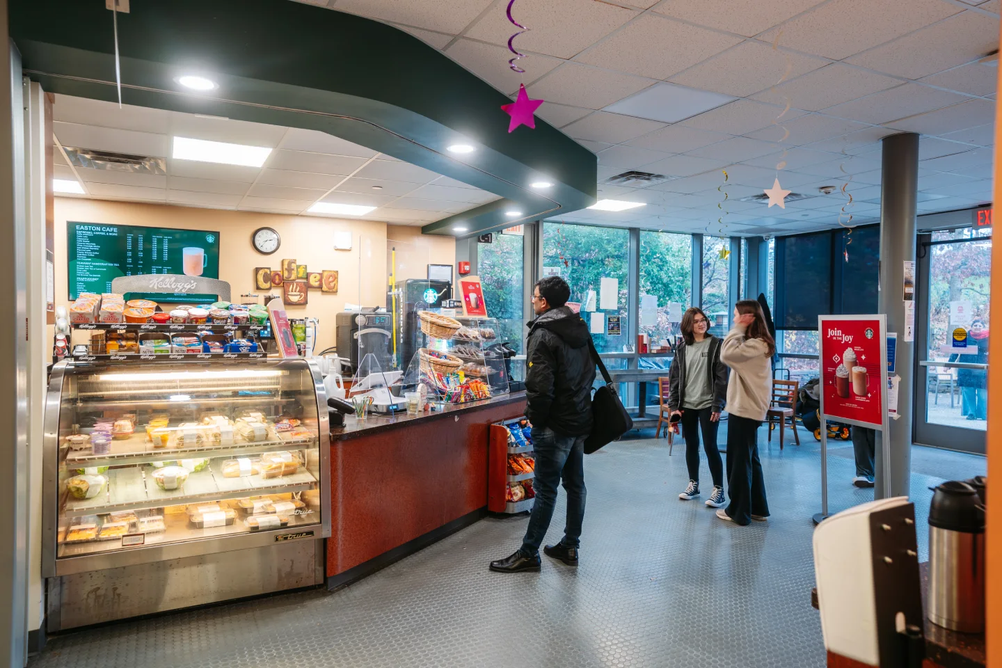 A man orders at the Easton Cafe while two students stand behind him in line.