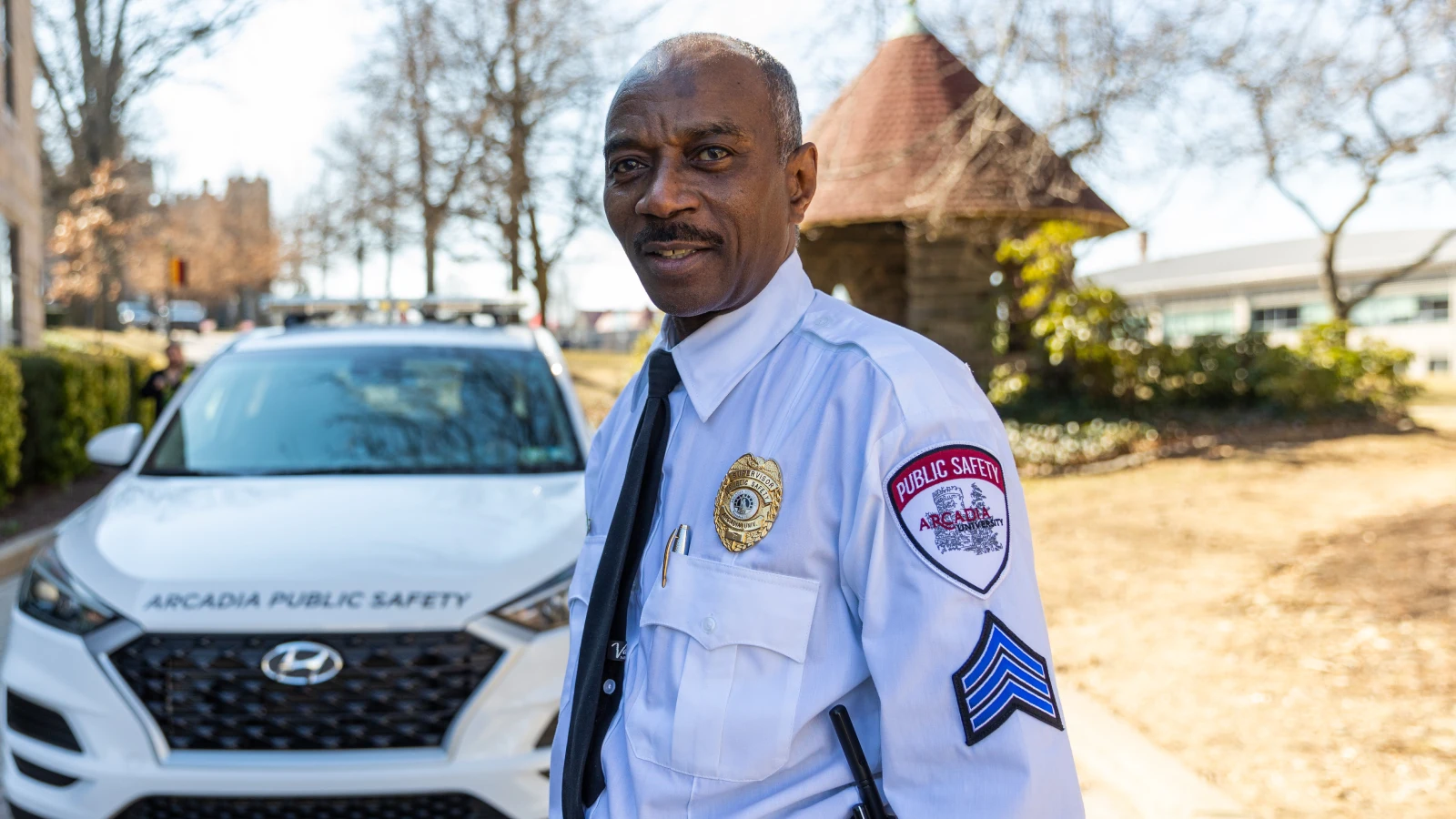 Senior Sergeant Bruce Gant stands for a photo while wearing his uniform in front of an Arcadia Public Safety vehicle.