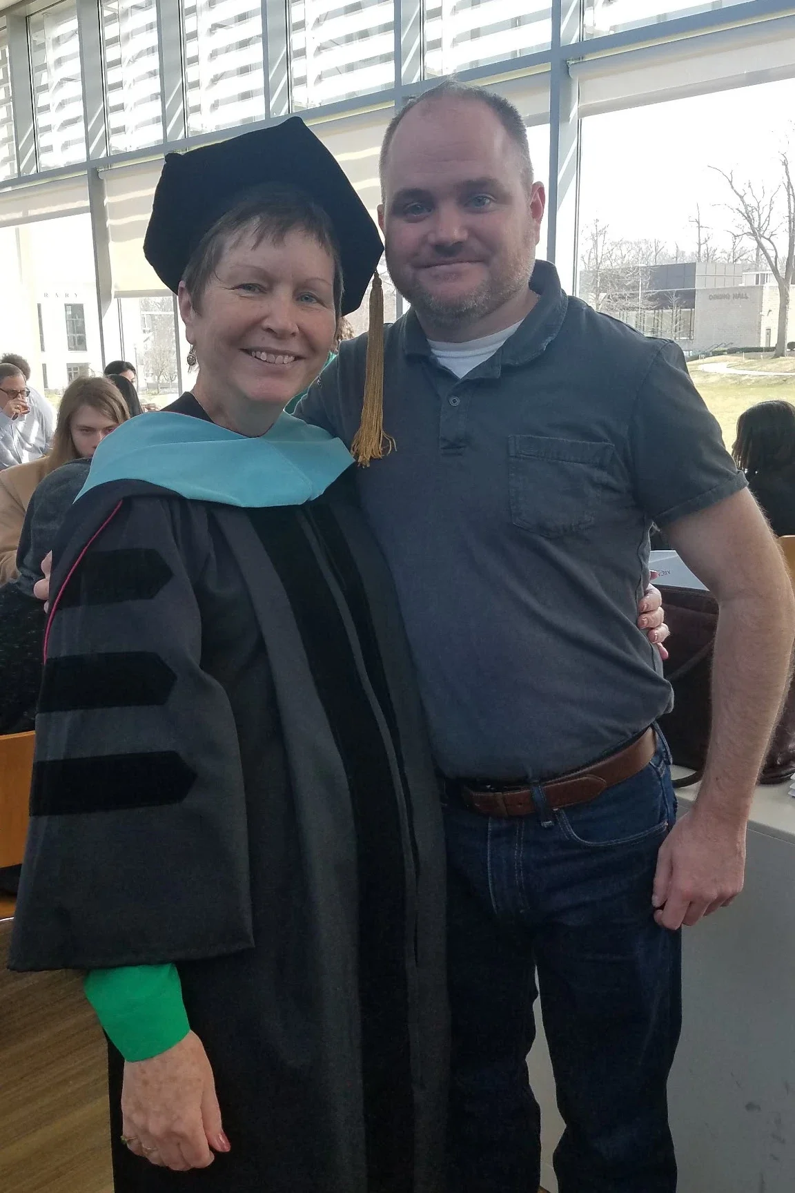 An older woman in a graduation gown poses with a man on the Arcadia campus.