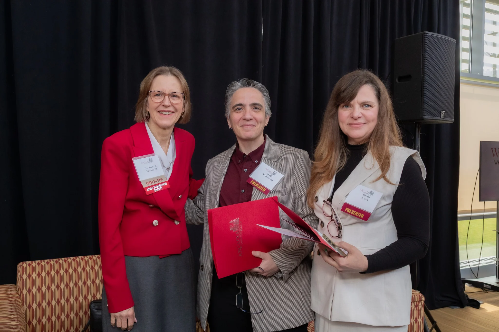 Three women pose for a picture after the two presenters have given the woman on the left side her award.