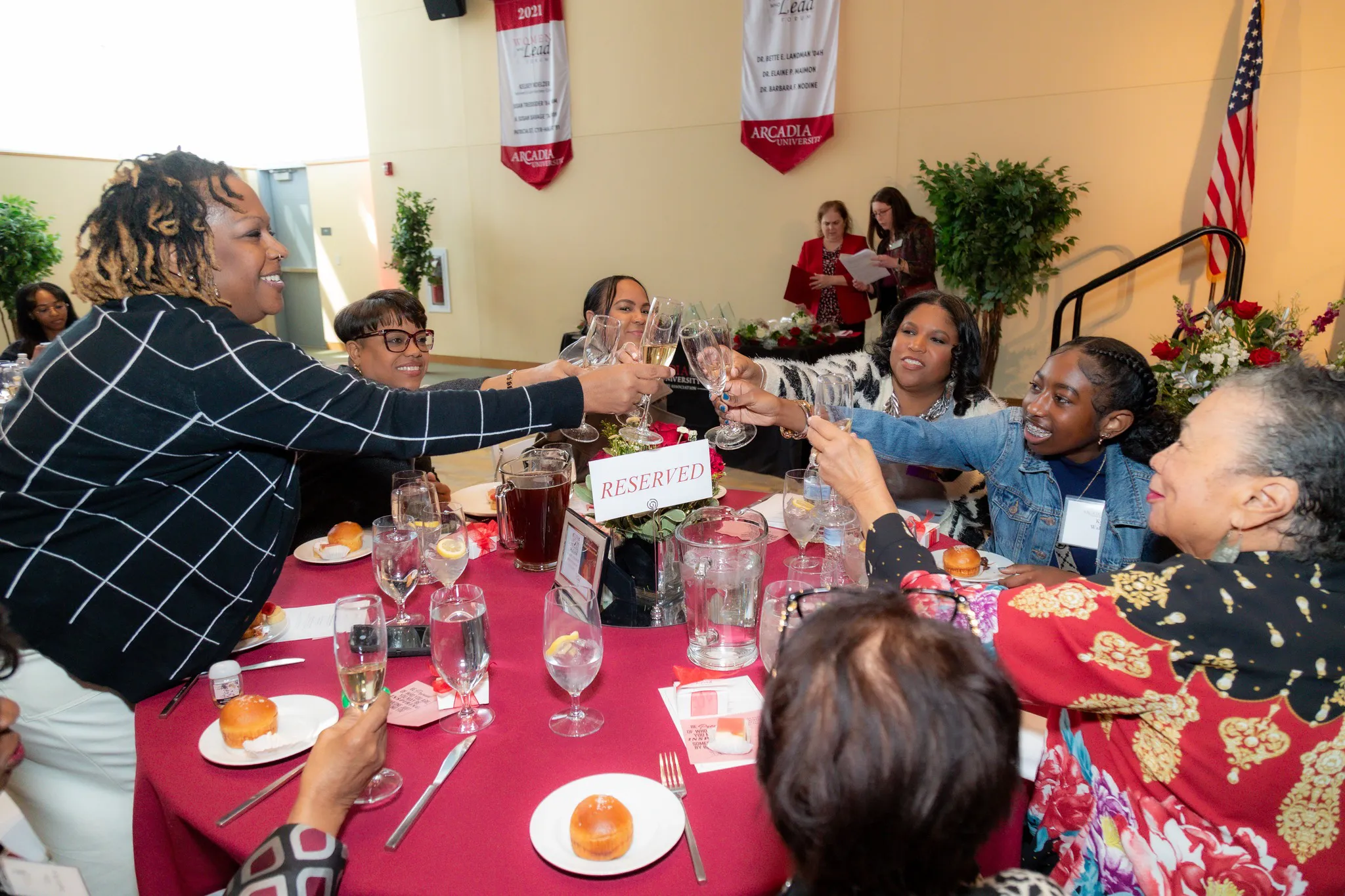 A group of women at a table raise their glasses and have a toast.