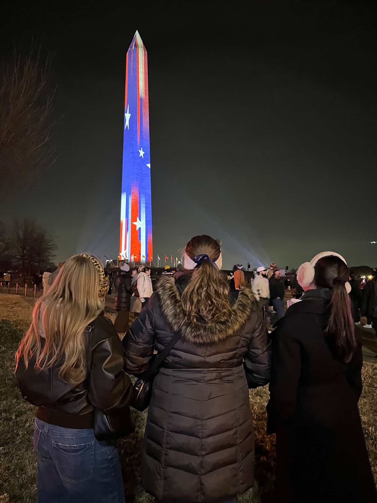 Lily Roberti ’28 and friends standing in front of the Washington Monument with an American flag lit up on it.