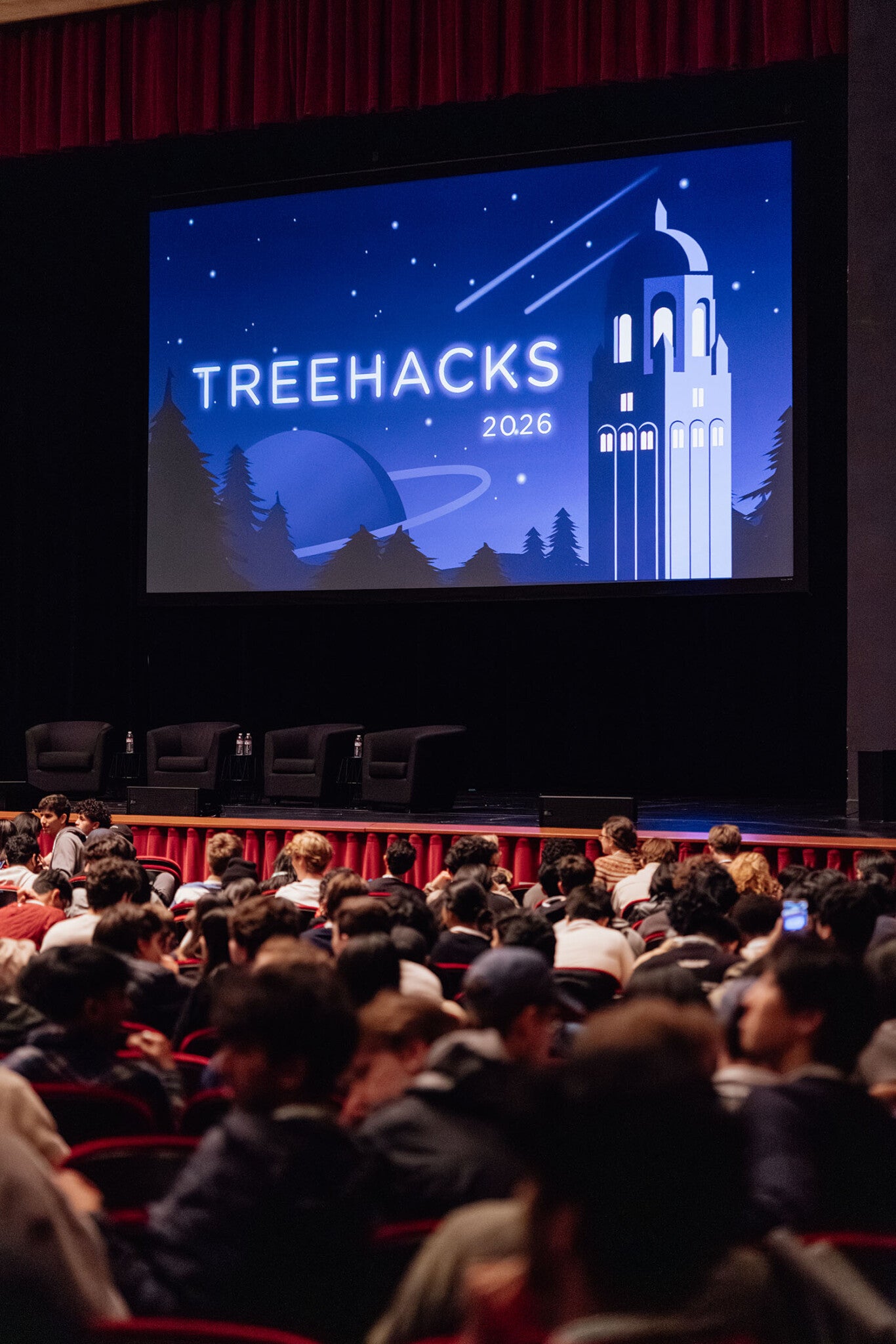 A projector showing "Treehacks 2026" on a screen in front of an audience.