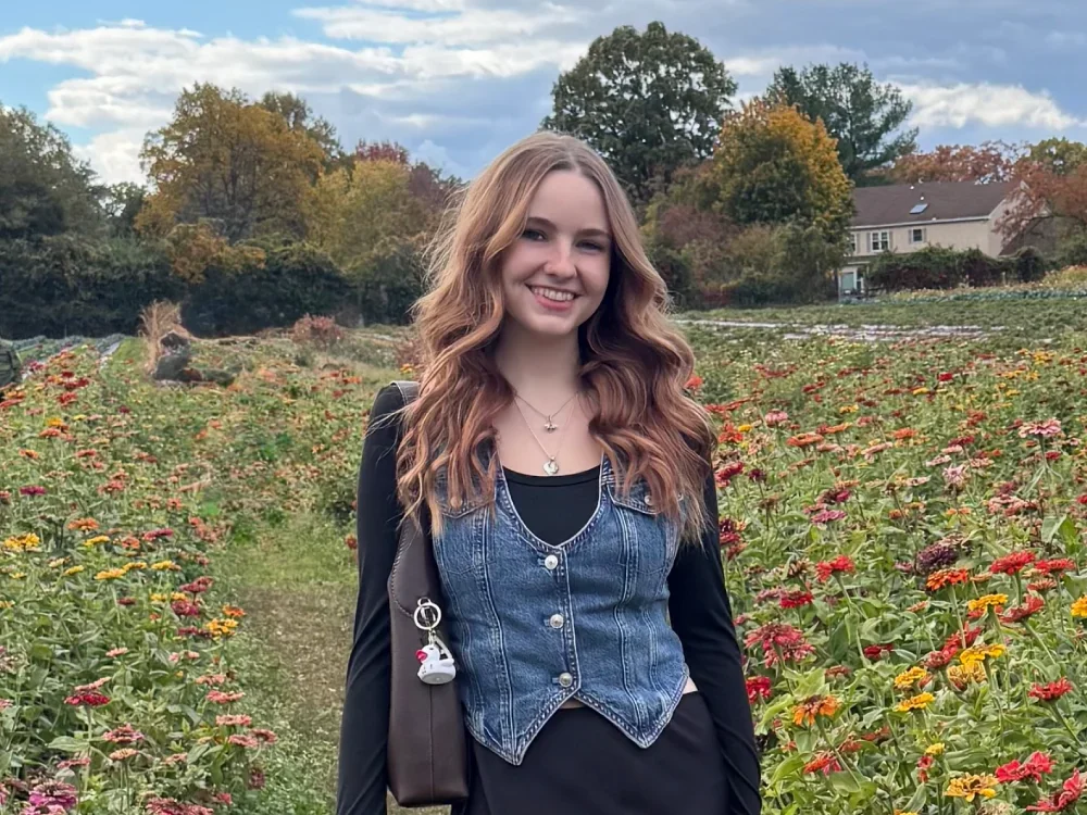 Michelle Freeland '27 stands in a field of flowers while smiling.