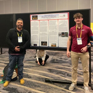 Dr. Martín and Aidan Murray pose in front of their research poster.