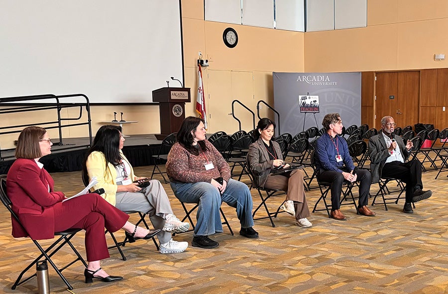 A panel of experts sits in chairs at the front of the room. Panelists include Otruba; Denisse Agurto, executive director of Unides Para Servir Norristown; Stephanie Vincent, founder and leader of Community for Change Montgomery County; Hyeonock “Mel” Lee, executive director of the Woori Center; Josh Blakesley, executive director of the Welcome Project PA; and State Sen. Art Haywood.