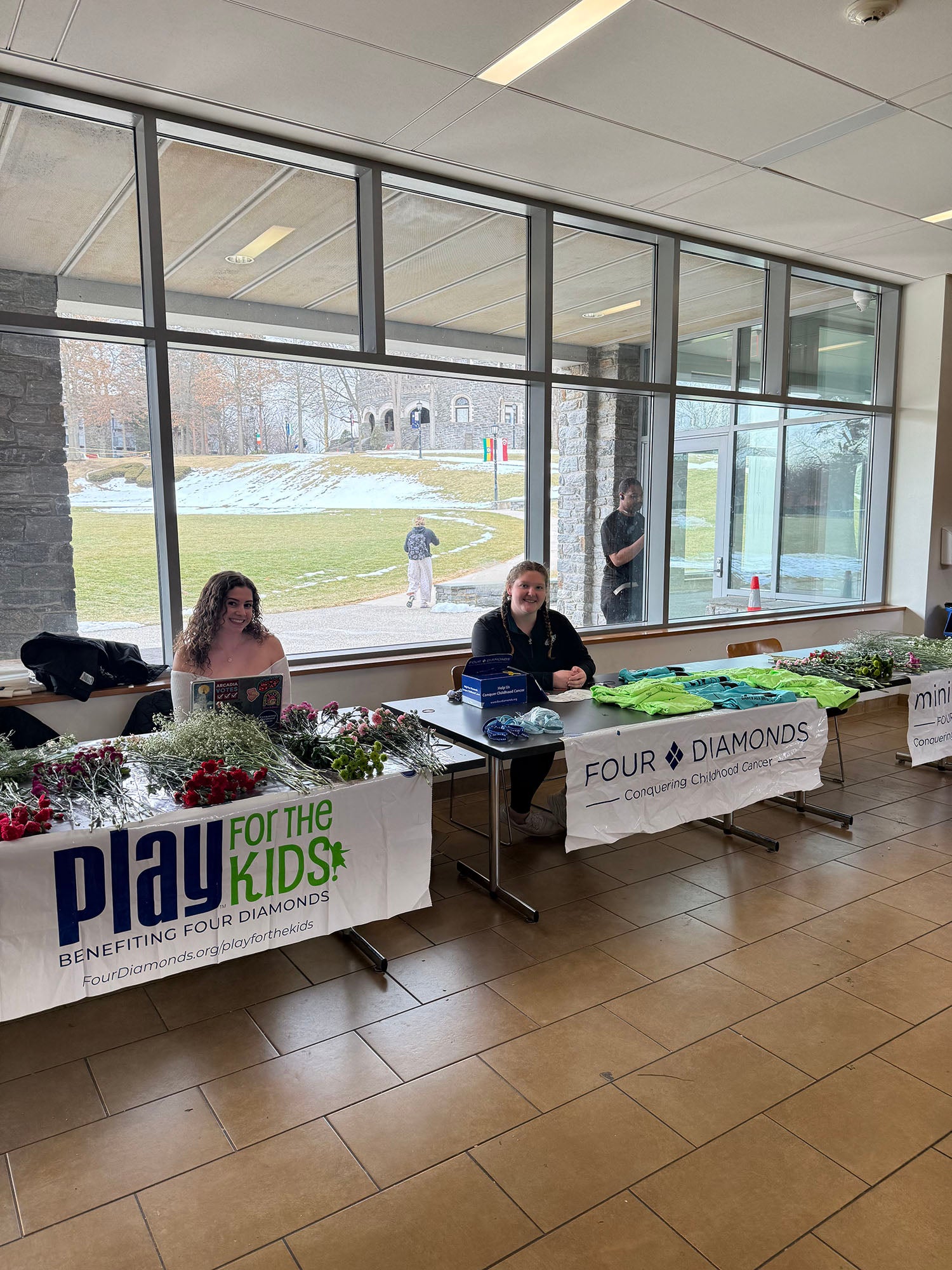 Arcadia FTK tables set up in the Chat with flowers on one side and t-shirts on the other.