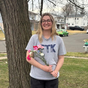 Morgan Kiefer ’26 wearing an FTK shirt and holding a bouquet.