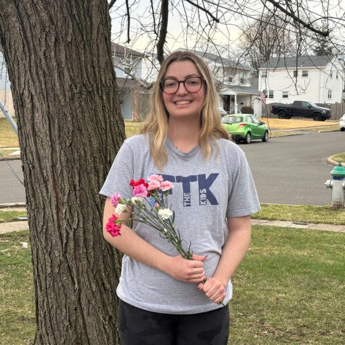 Morgan Kiefer ’26 wearing an FTK shirt and holding a bouquet.
