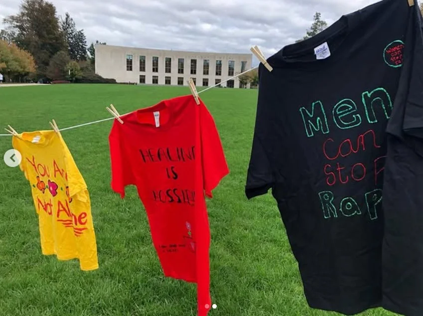 Colorful t-shirts hanging on a clothesline by hand during a campus event.