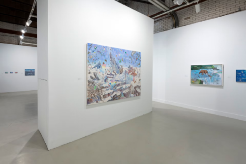 a photo of a colorful painting from an angle on a single white wall.