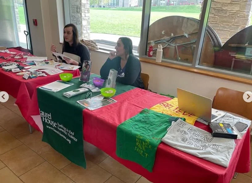 Staff members managing a table during an indoor campus event.