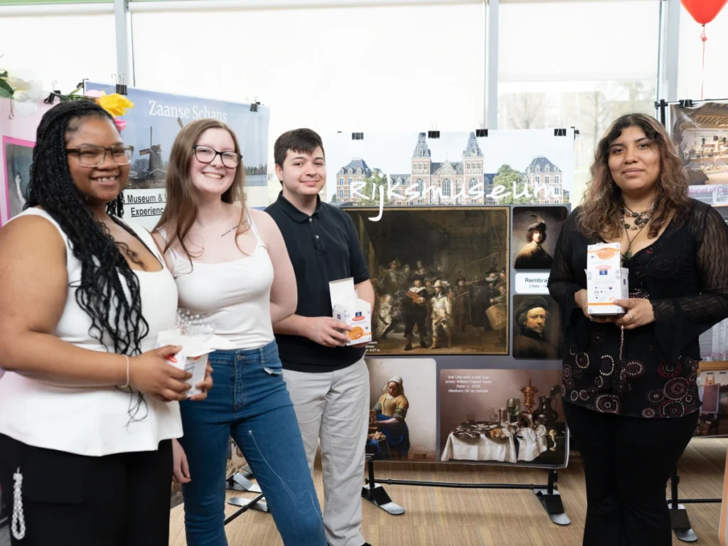 Four students pose for a photo in front of posters at Global Expo.
