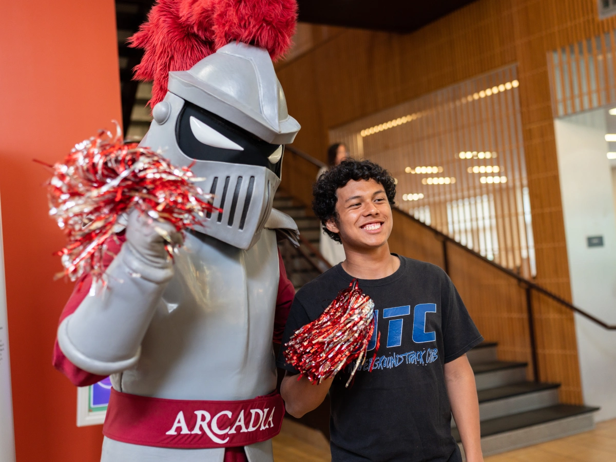 A student poses for a photo with Archie the Knight on Scarlet & Grey day.