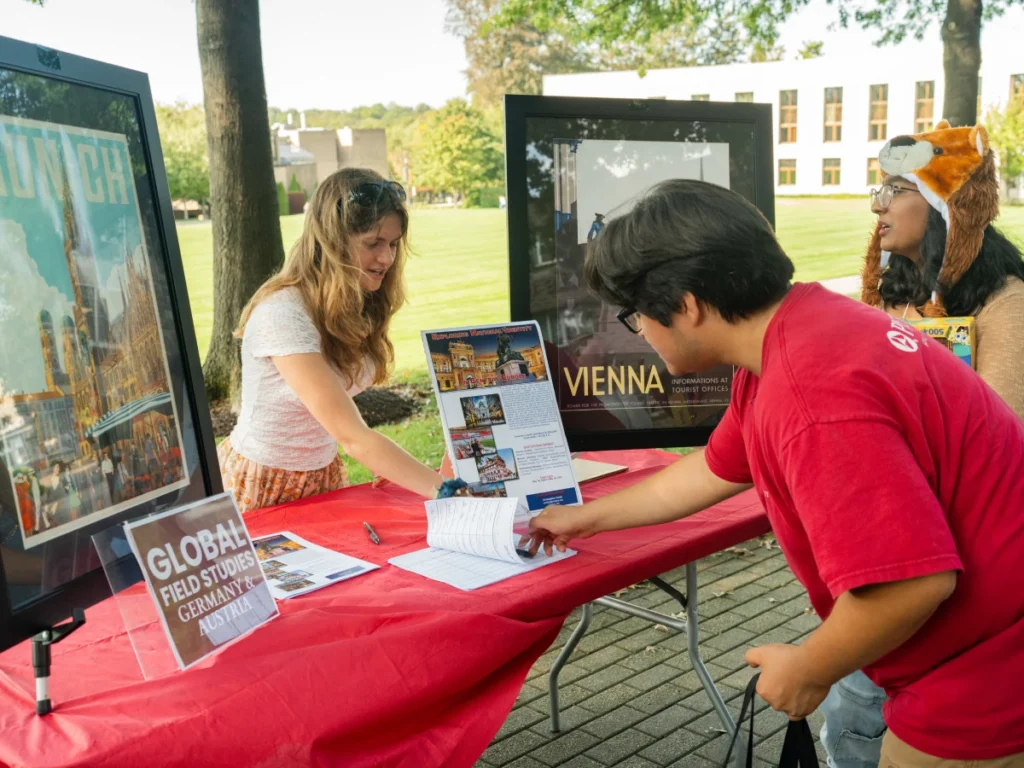A student signs an interest form at a table at the Study Abroad Fair at Arcadia.