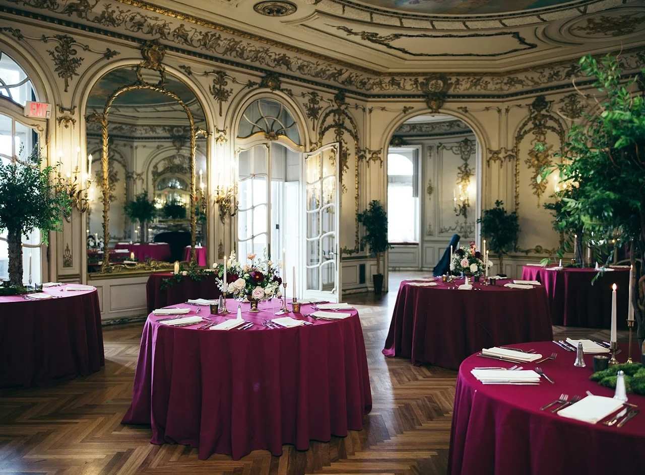 Tables in the Mirror Room are set with burgundy tablecloths and formal silver place settings.