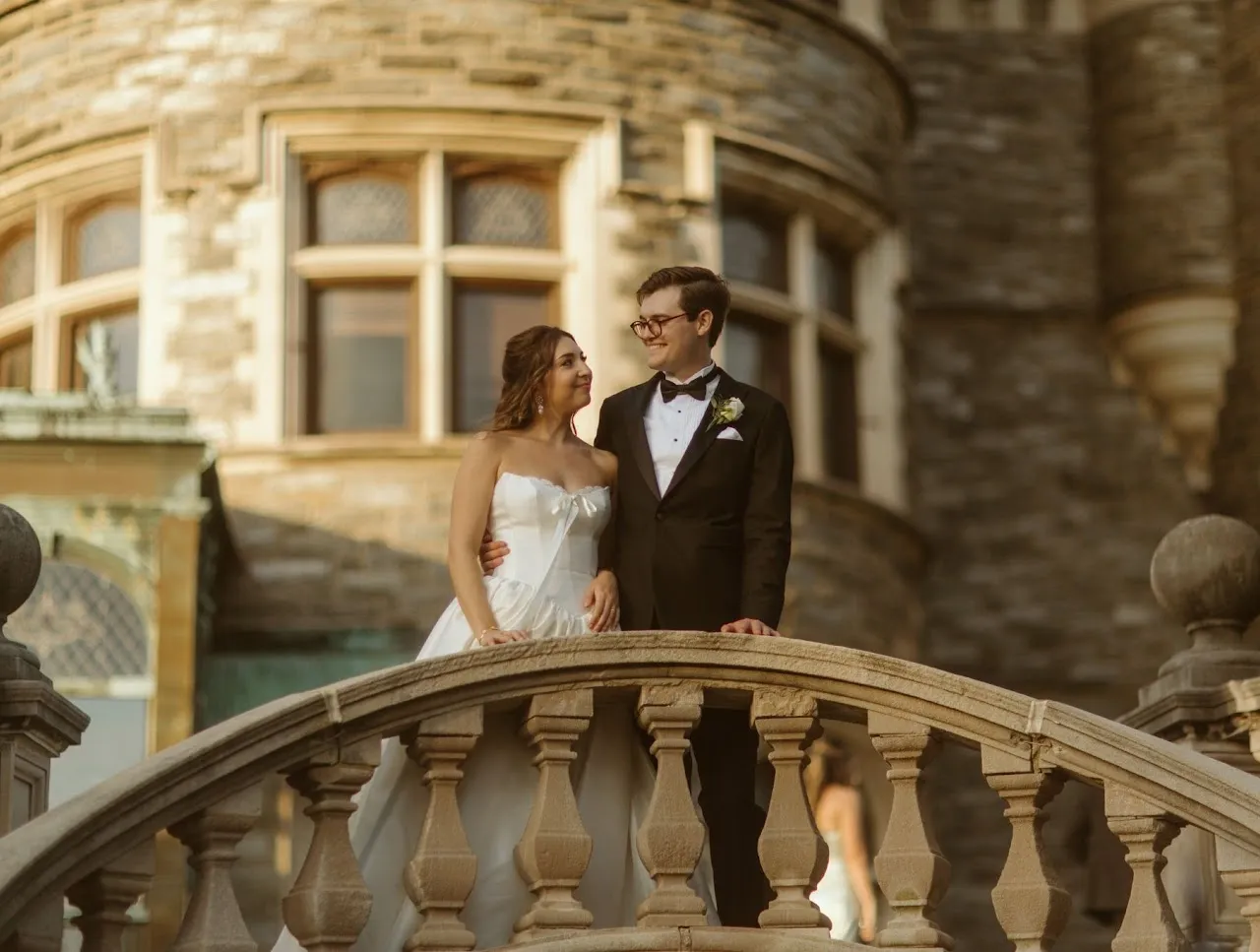 A wedding couple stands on a stone ledge along the outdoor staircase of Grey Towers Castle.