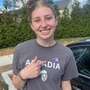 Shelby Jones '26 smiles for the camera while pointing to an "I Voted" sticker she is wearing.